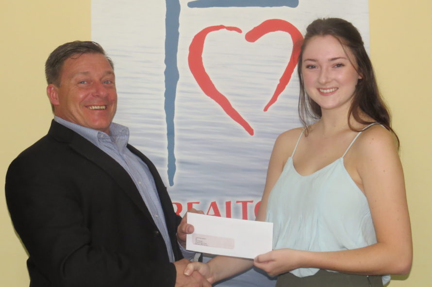 Trent Wilkins, president of Greater Moncton REALTORS® du Grand Moncton, presents a bursary to Eryn McNally