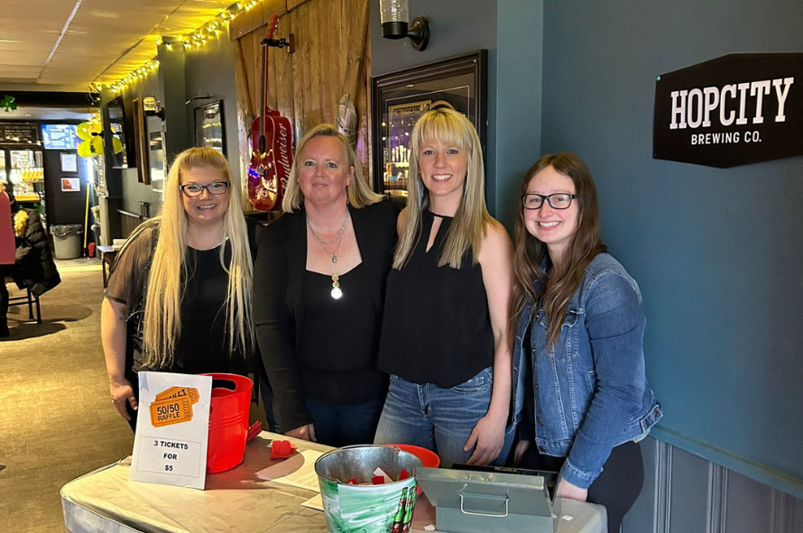 Four volunteers stand at a raffle table raising money