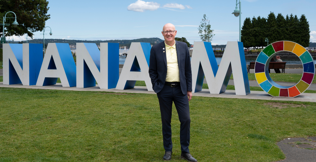 Ken Hammer stands in front of a 3-D Nanaimo sign -- Ken Hammer se tient devant un panneau 3D Nanaimo