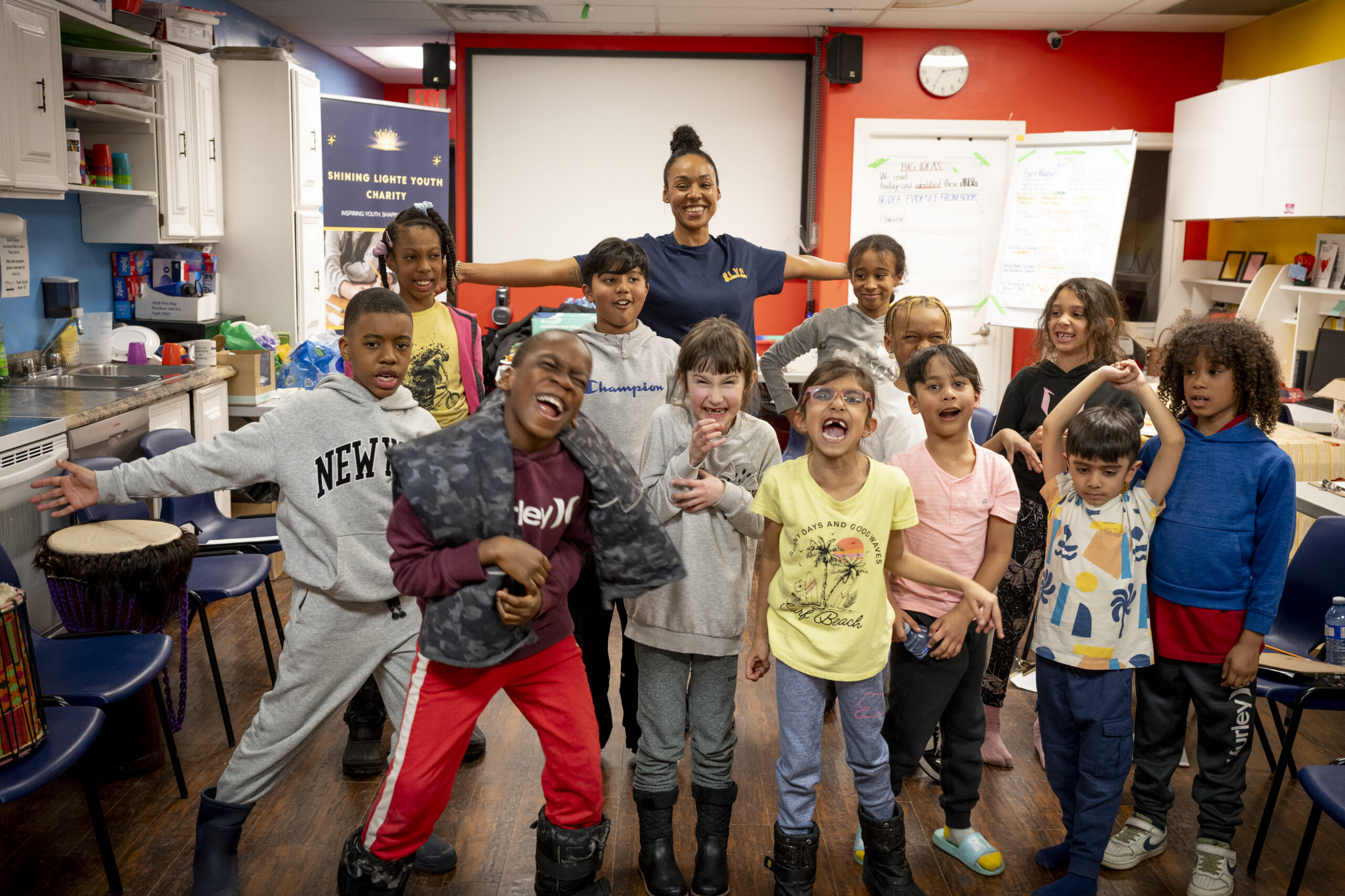 Kandice stands smiling behind a group of children participating in a Shining Lighte Youth program.