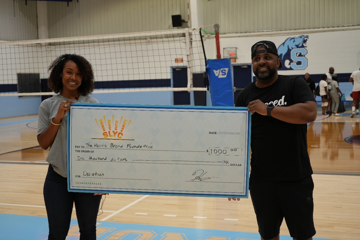 Kandice stands with the ED of the Harris Brand Foundation holding a large donation to his organization.